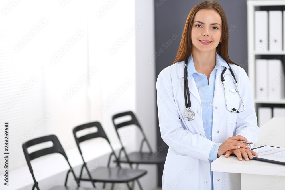 Doctor woman at work. Portrait of female physician standing near reception desk at clinic or emergency hospital. Medicine and healthcare concept Doctor woman at work. Portrait of female physician standing near reception desk at clinic or emergency hospital. Medicine and healthcare concept