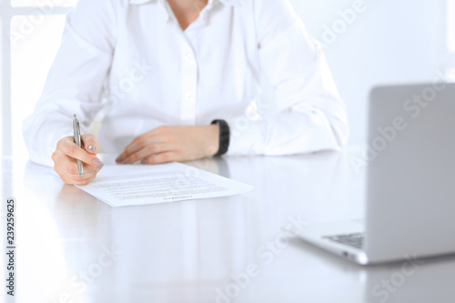 Close-up of female hands with pen over document   business concept. Lawyer or business woman at work in office