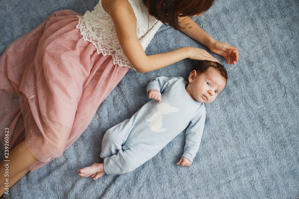 Cute happy girl holding her newborn baby brother. Gray background. Pretty baby boy in blue clothes Cute happy girl holding her newborn baby brother. Gray background. Pretty baby boy in blue clothes
