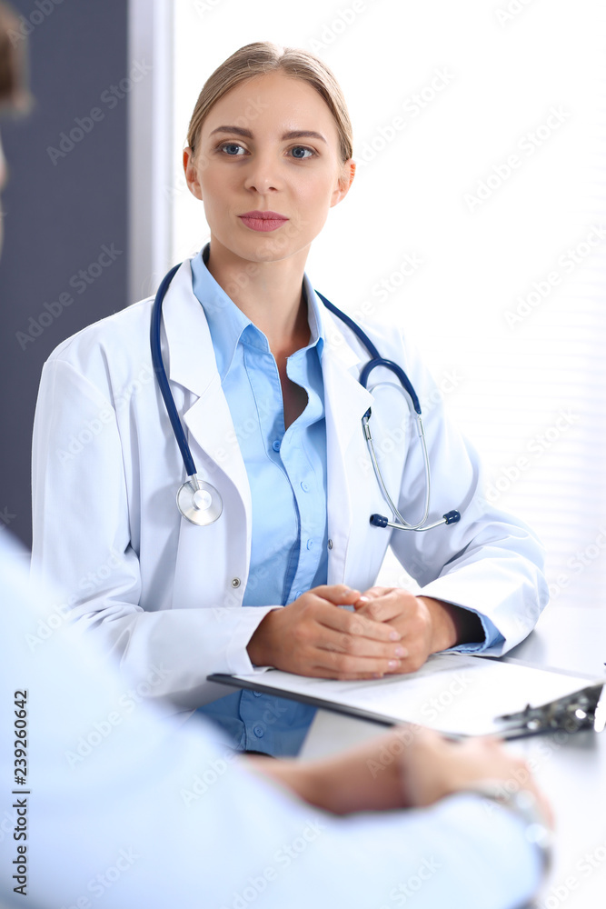 Doctor and patient in hospital. Beautiful blonde physician consulting business man about his health. Medicine concept Doctor and patient in hospital. Beautiful blonde physician consulting business man about his health. Medicine concept