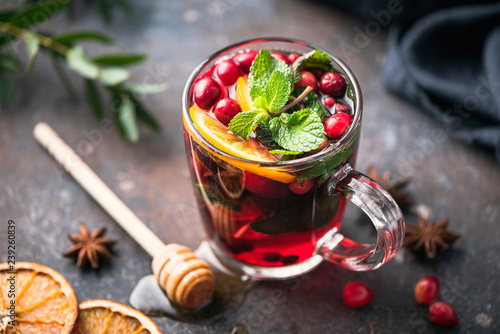 Hot spiced cranberry tea with cinnamon, orange peel, star anise and honey in glass cup