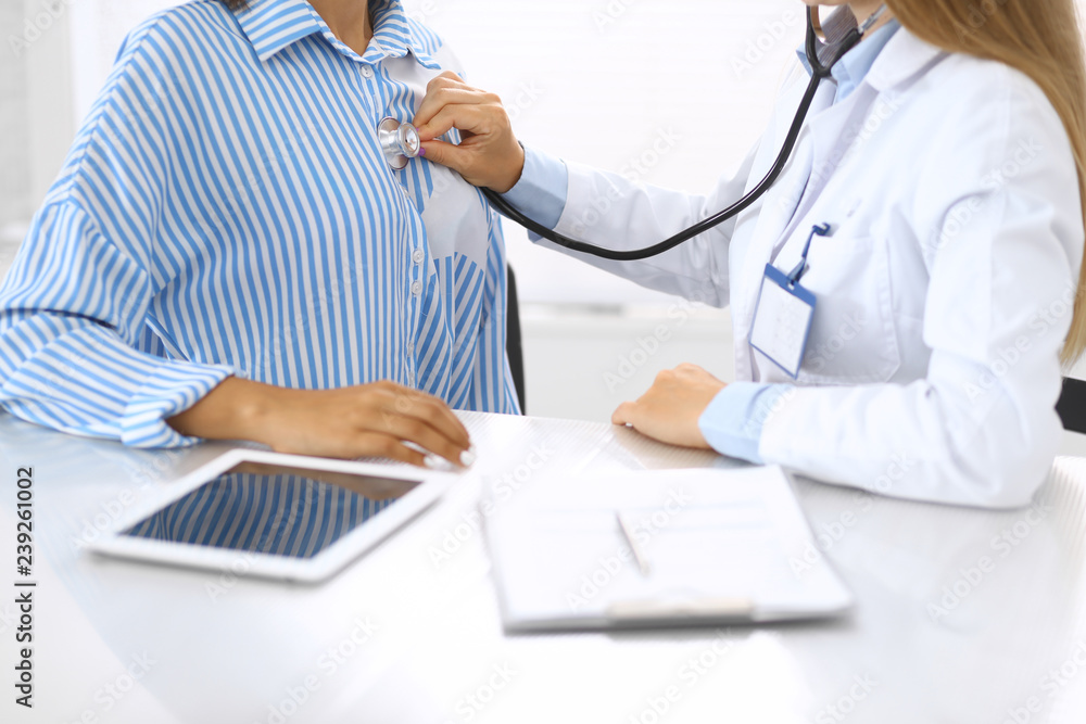 Doctor with a stethoscope in the hand. Physician examines her female patient. Health care and medicine concepts Doctor with a stethoscope in the hand. Physician examines her female patient. Health care and medicine concepts