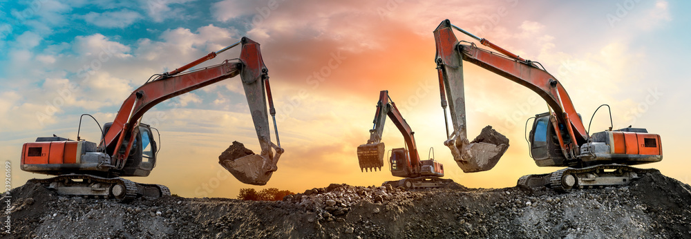 Three excavators work on construction site at sunset,panoramic view - obrazy, fototapety, plakaty 