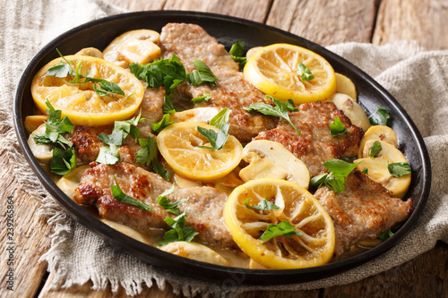 Italian recipe of delicious veal scaloppini cooked with mushrooms and lemons in a spicy sauce, close-up in a pan. horizontal photo