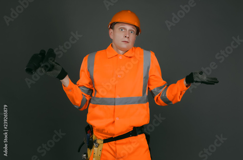Фотография Geodesist or builder foreman with a binoculars is shrugging by his shoulders isolated on gray background