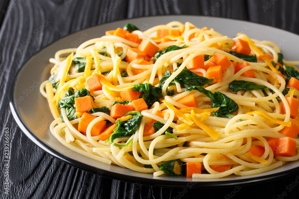 Low-calorie lunch of spaghetti with pumpkin, spinach and cheddar cheese close-up on a plate. horizontal Low-calorie lunch of spaghetti with pumpkin, spinach and cheddar cheese close-up on a plate. horizontal
