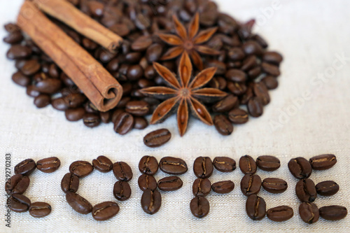 Roasted coffee beans, cinnamon sticks and star anise on the burlap with the inscription Coffee