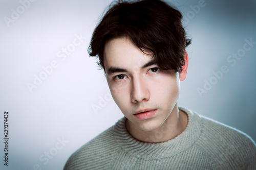 Studio portrait young man in grey sweater on dark background