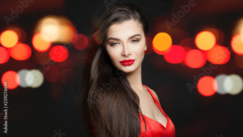 Glamorous woman with long dark hair and makeup on abstract night glitter bokeh background