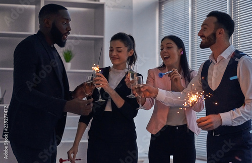 The four business people drinking champagne and holding sparklers