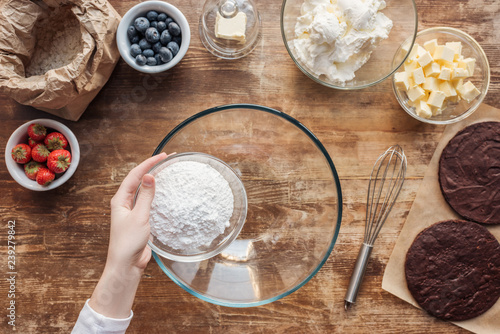 cropped shot of woman holding flour and preparing dough for delicious homemade cake