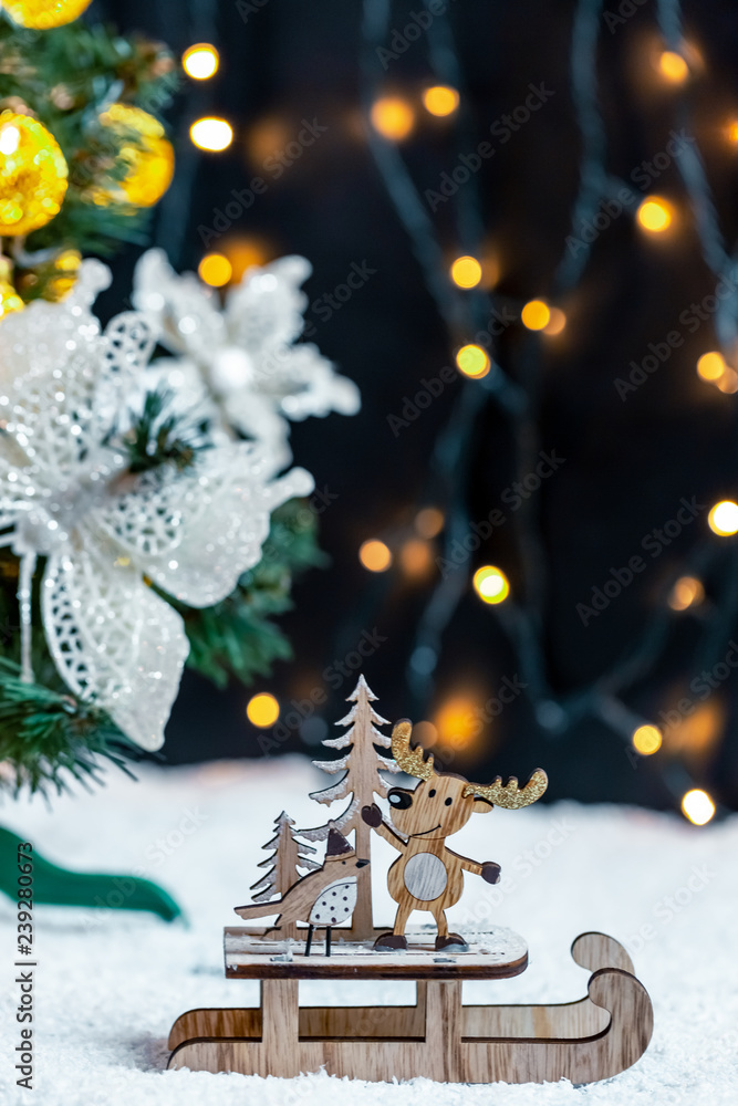 Wooden sleigh with deer and Christmas tree on snow on bokeh background garland