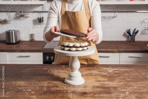 mid section of woman in apron preparing delicious whoopie pie cake in kitchen