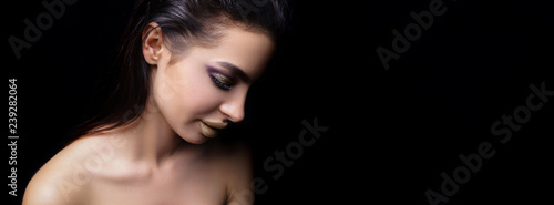 High Fashion model girl in colorful bright sparkles posing in studio on black background, close-up portrait of beautiful woman, trendy glowing make-up. Art design colorful make up. 
