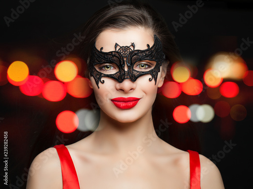 Young smiling woman in sexy carnival mask on abstract red night glitter bokeh background