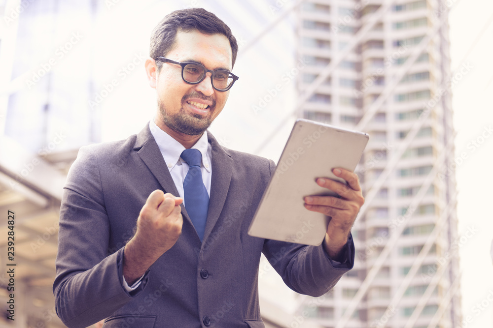 Happy Successful of Businessman working online with digital tablet while standing outside an office in the city Happy Successful of Businessman working online with digital tablet while standing outside an office in the city