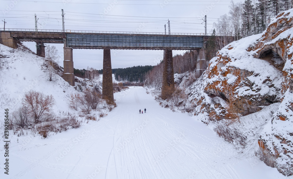 Obraz premium Railway bridge over the frozen river. Family of three people in the center.