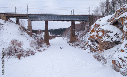 Railway bridge over the frozen river. Family of three people in the center.