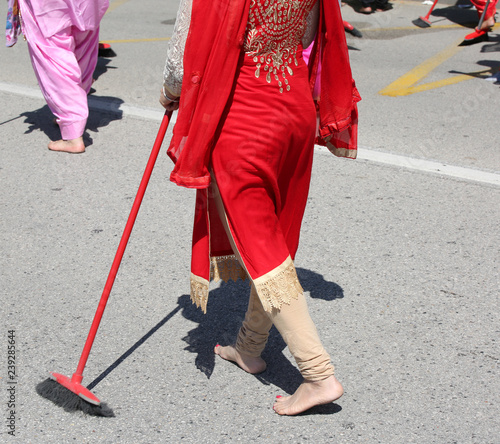 barefoot Sikh woman sweeps the road with her broom