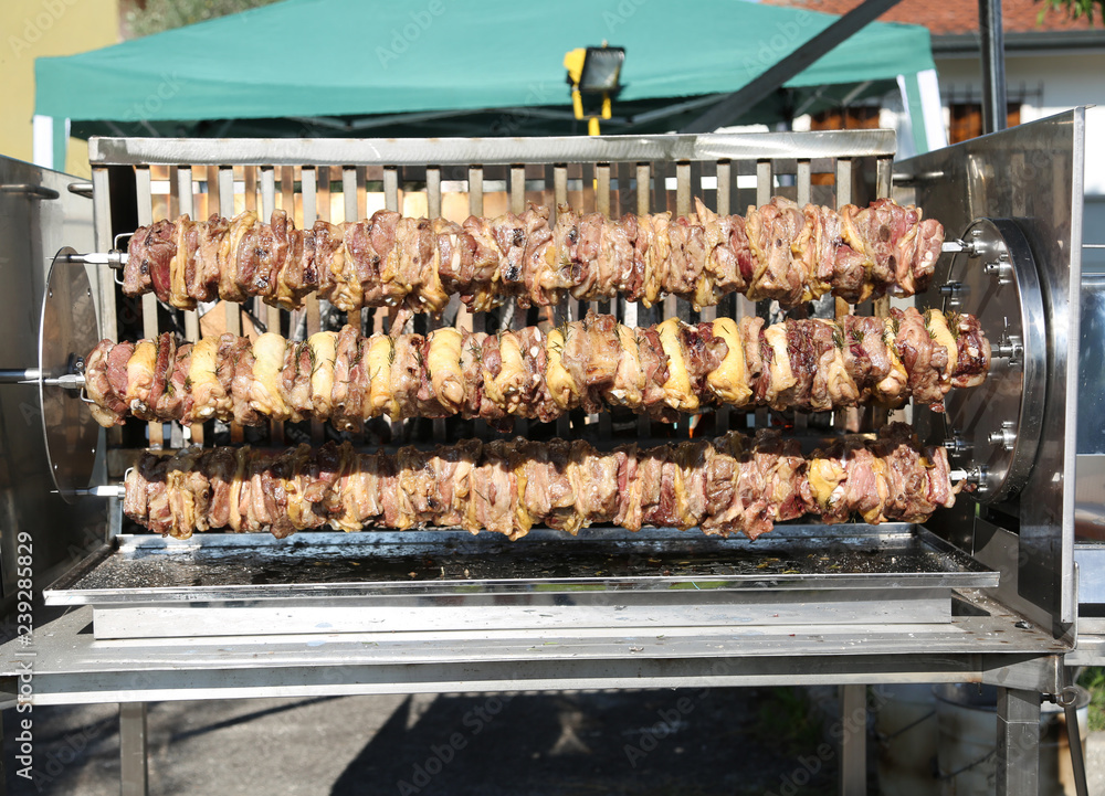 skewers of chicken meat while cooking in the outdoor rotisserie