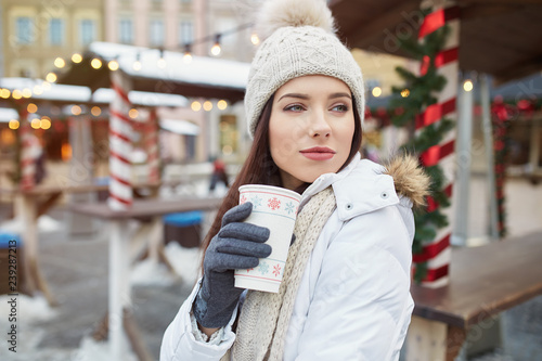 Young pretty girl is drinking a hot drink on the christmas market. Joy of winter time © Izabela Magier