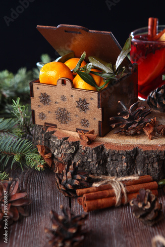 Wooden carved box box with tangerines on a wooden background with fir branches. Concept of still life and holiday. New year or Christmas.