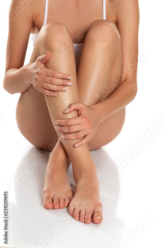 woman tenderly touching her legs on white background