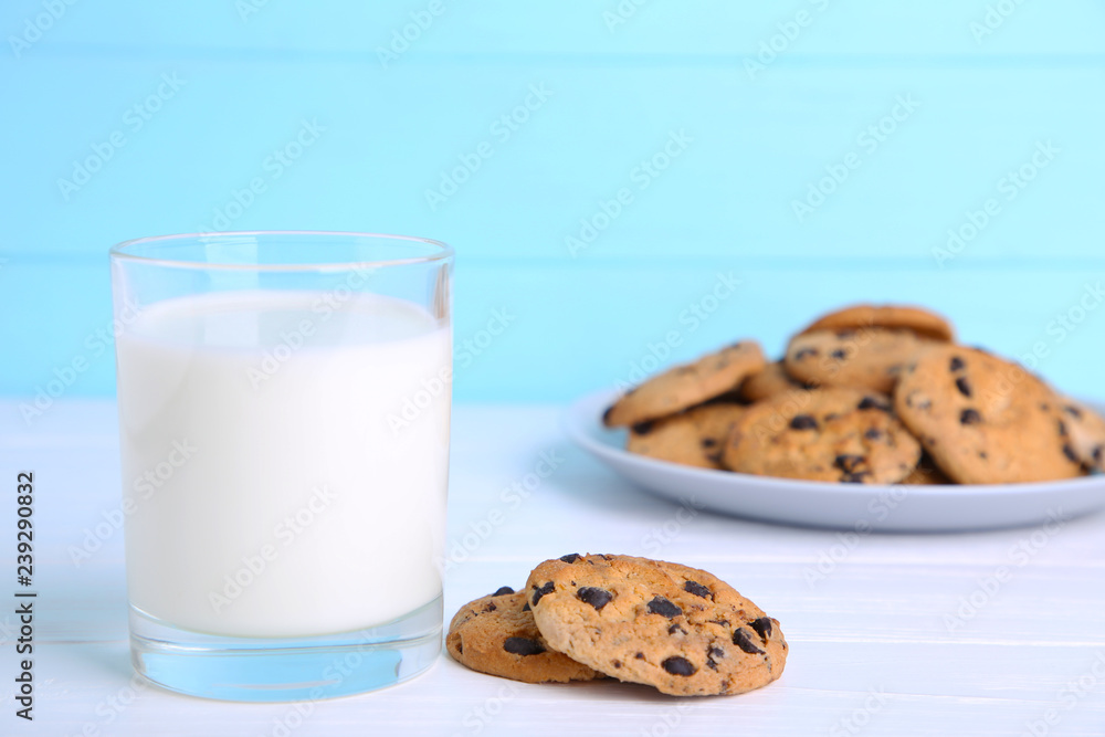 Glass of milk and chocolate cookies on plate on blue background Glass of milk and chocolate cookies on plate on blue background