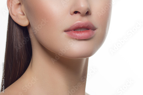 Cosmetics, makeup and trends. Bright lip gloss and lipstick on lips. Closeup of beautiful female mouth with natural lip makeup. Beautiful part of female face. Perfect clean skin in natural light