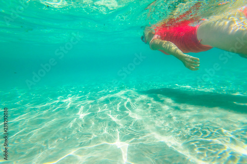 Female apnea underwater with pink wetsuit. Woman snorkeler swims in Denmark, Western Australia. Greens Pool, William Bay NP. Watersport activity in Australia. Tropical destination holiday concept.