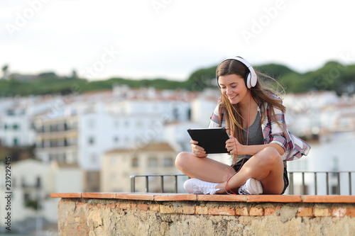 Happy teen watching and listening video on a tablet