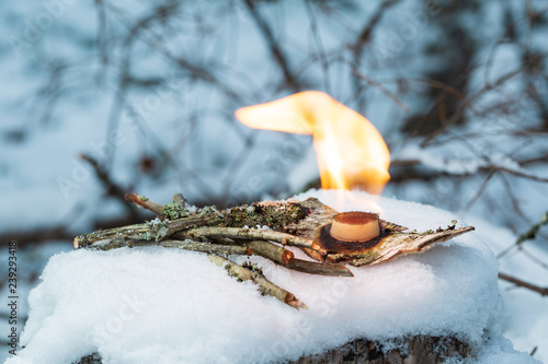 Dry fuel in the form of dry alcohol for ignition. In the frame of twigs, birch bark, dry fuel. The background of winter forest is blurred