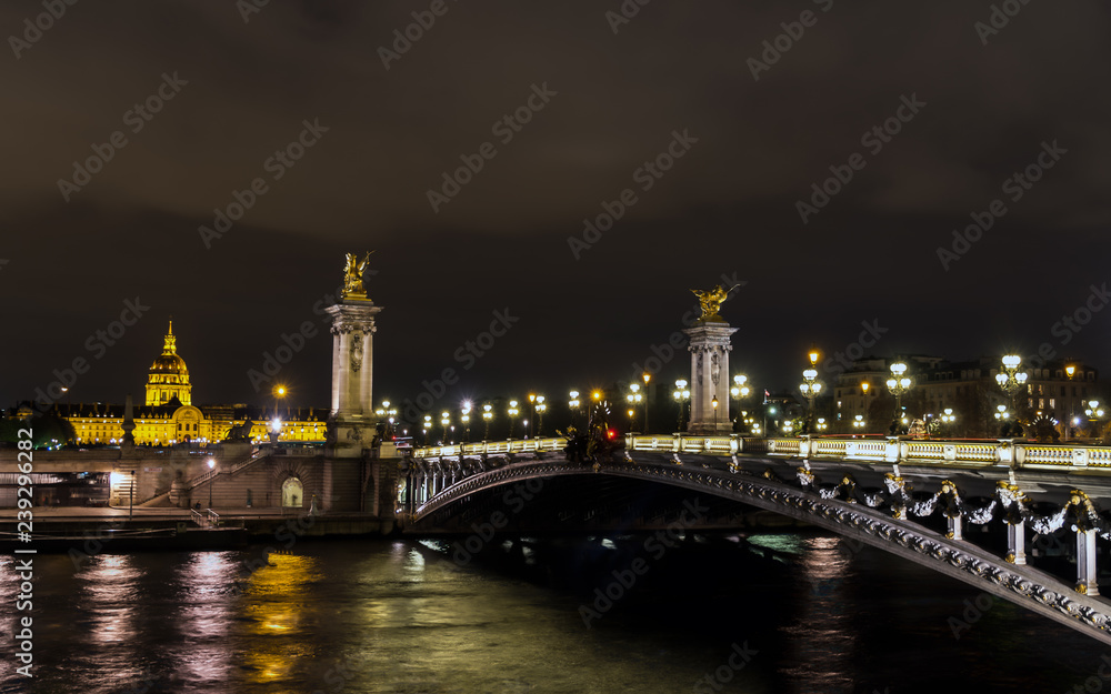 Pont Alexandre III on Seine River with Invalid dome in background at night - Paris France Pont Alexandre III on Seine River with Invalid dome in background at night - Paris France
