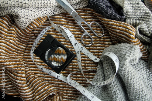 Background of bobbin, scissors, rule, magnifier with yarn and knitted fabric.