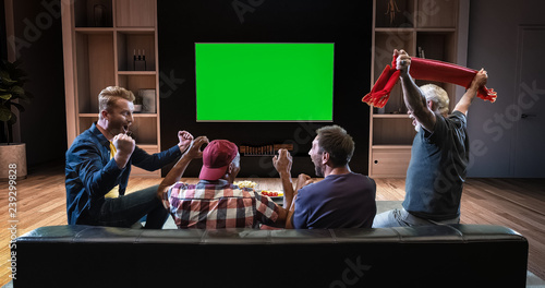 Foto A group of fans is watching a TV and celebrating some joyful sports moment, sitting on the couch in the living room