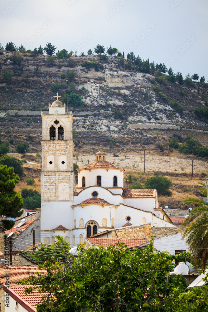 A large white the holy cross church with a red tile roof and a tower with a bell tower in the Lefkara village mountains Troodos on the island of Cyprus