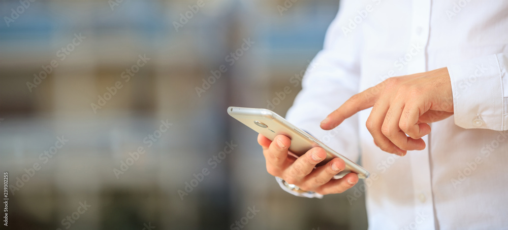 Man holding phone. Young left handed businessman in business wear using a mobile, closeup view on smartphone, banner