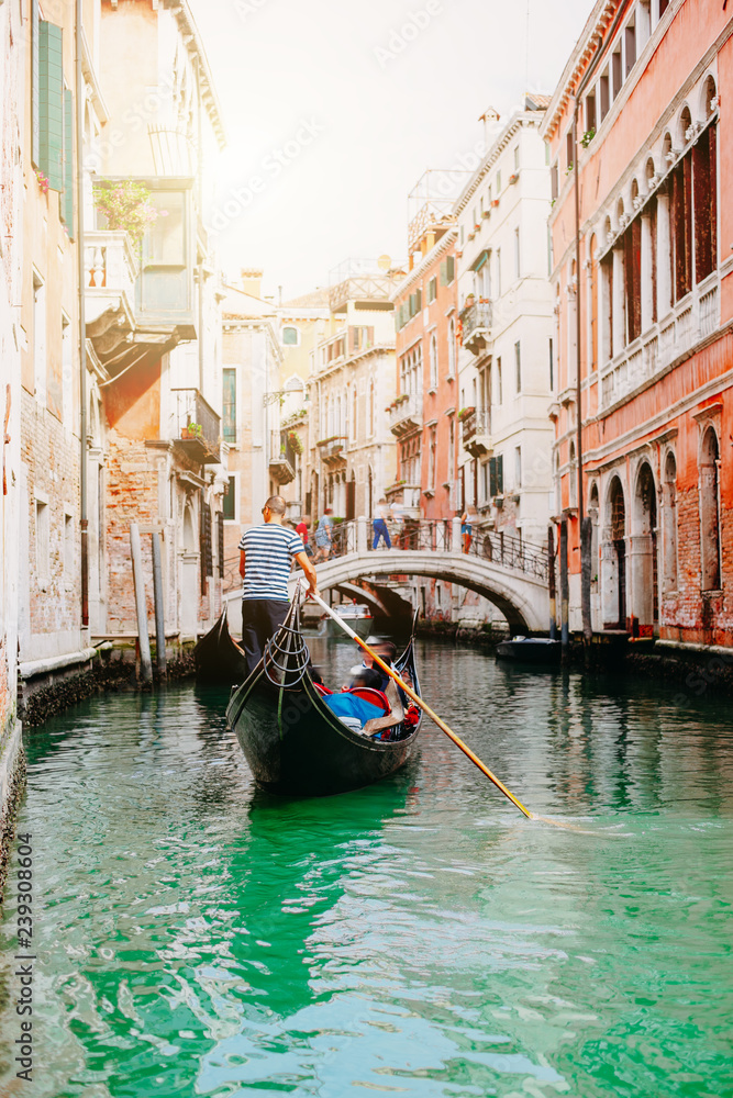Venezianer fährt mit Gondel durch einen Kanal in Venedig im Sommer