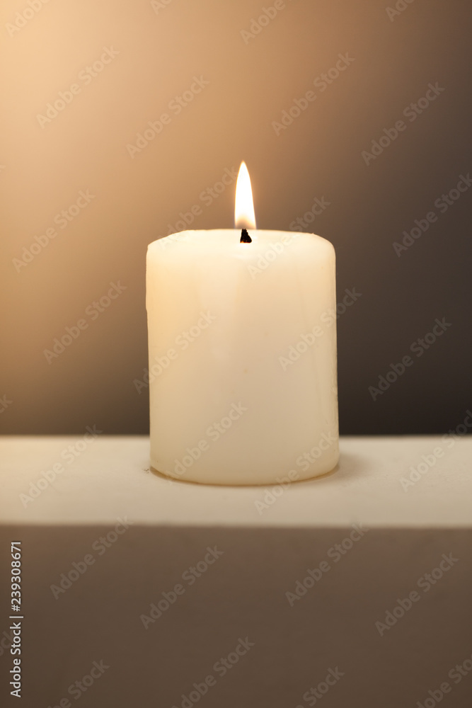 Large lighted candle on a shade contrast background. Large lighted candle on a shade contrast background.
