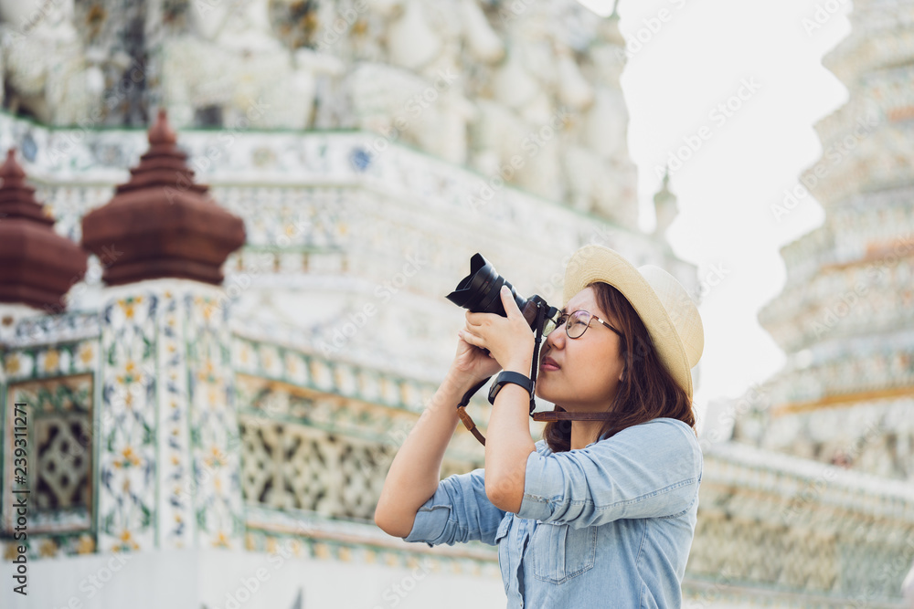 Beautiful woman tourist Held camera to capture the memories. Wat Arun Temple in Thailand. using as background  travel concept with copy spaces for your