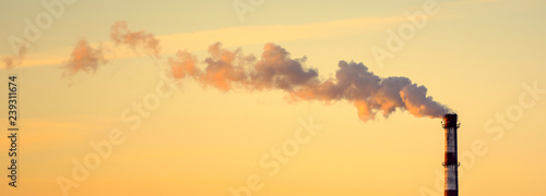 Photo of factory pipe with smoke at sunset