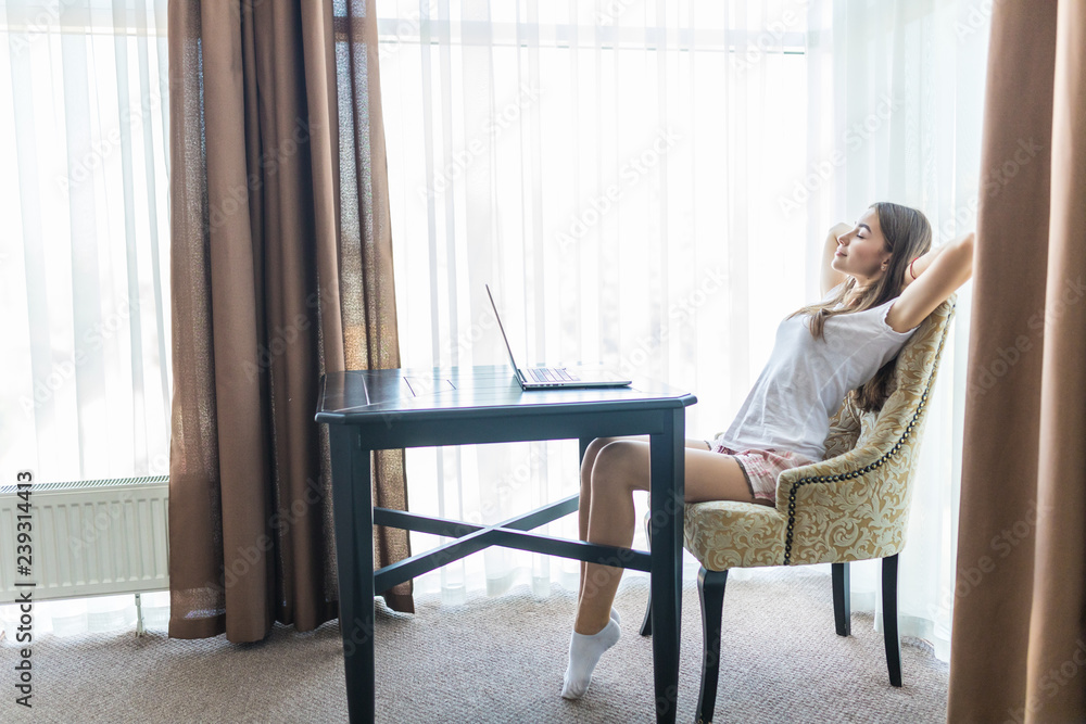 Satisfied woman with arms over head relaxing sitting on a chair with laptop at home