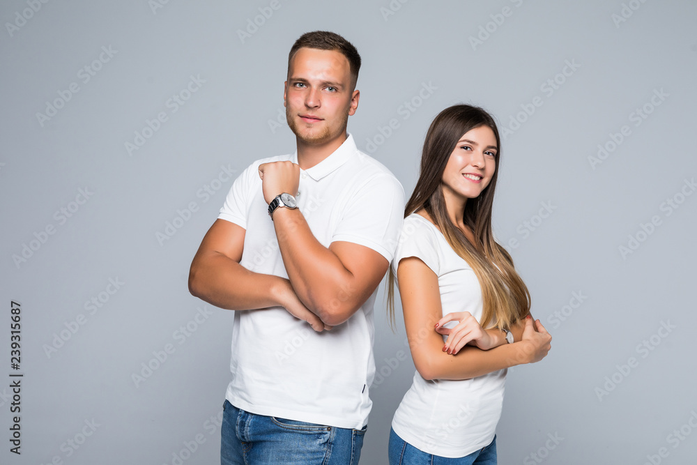 Attractive young couple standing back to back with arms crossed isolated on gray background Attractive young couple standing back to back with arms crossed isolated on gray background