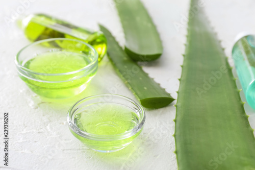 Aloe gel with leaves on white textured background