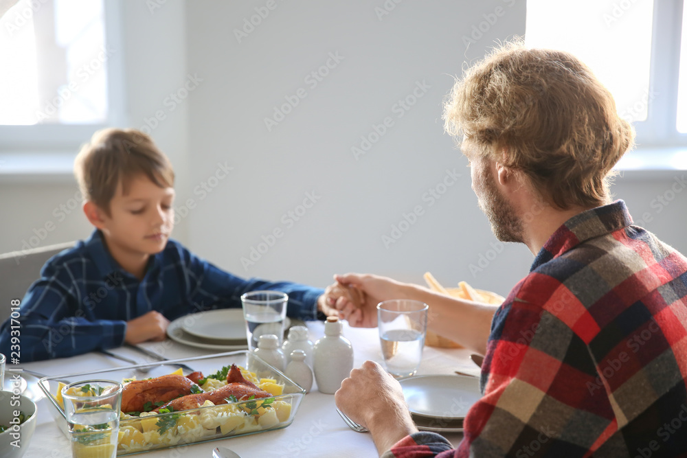 Father with son praying before meal at home Father with son praying before meal at home