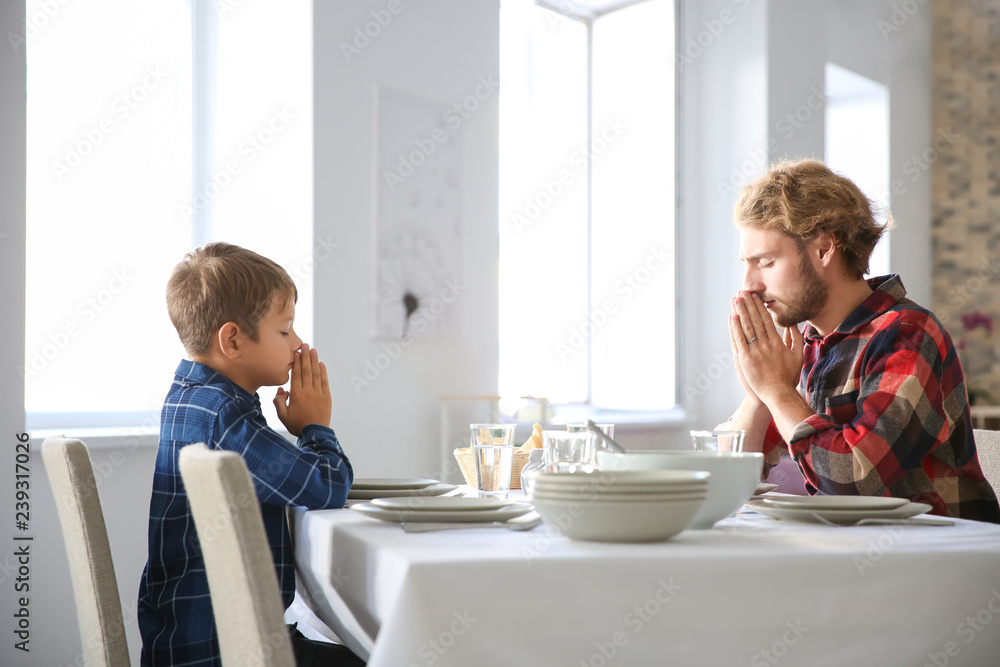 Father with son praying before meal at home Father with son praying before meal at home