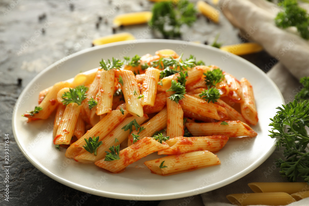 Plate with tasty penne pasta on grey table Plate with tasty penne pasta on grey table