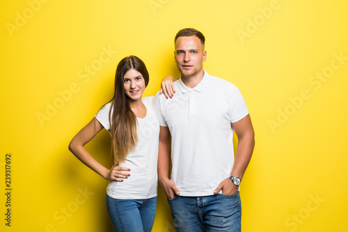 Portrait of happy lovely couple smiling and posing on camera together over yellow background