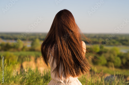 Young girl sits with his back to the camera and looks at nature