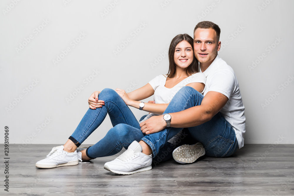 Beautiful couple in love on white background dressed in blue jeans and white undershirt Beautiful couple in love on white background dressed in blue jeans and white undershirt